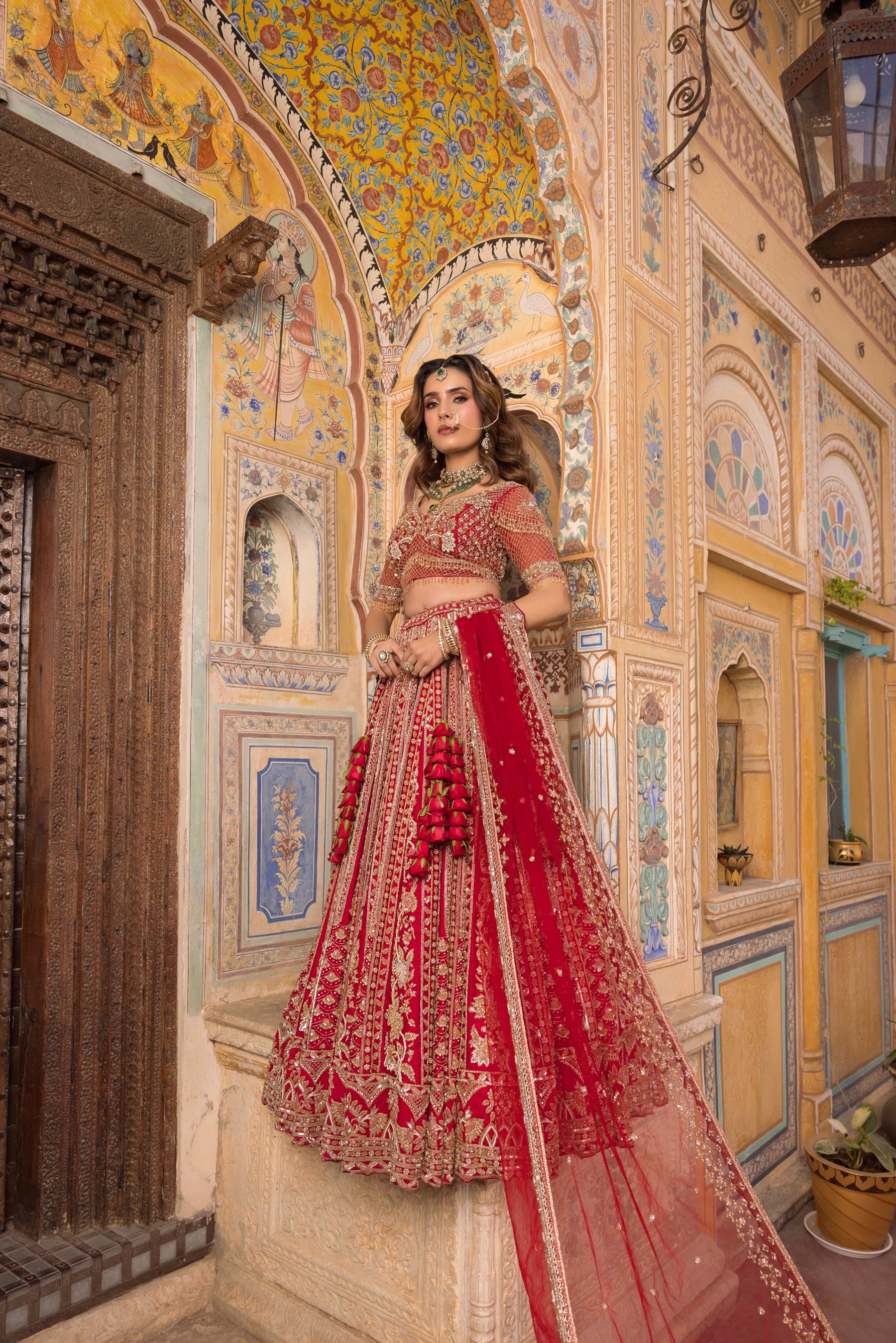 A bride in a painted corridor, dupatta trailing behind her