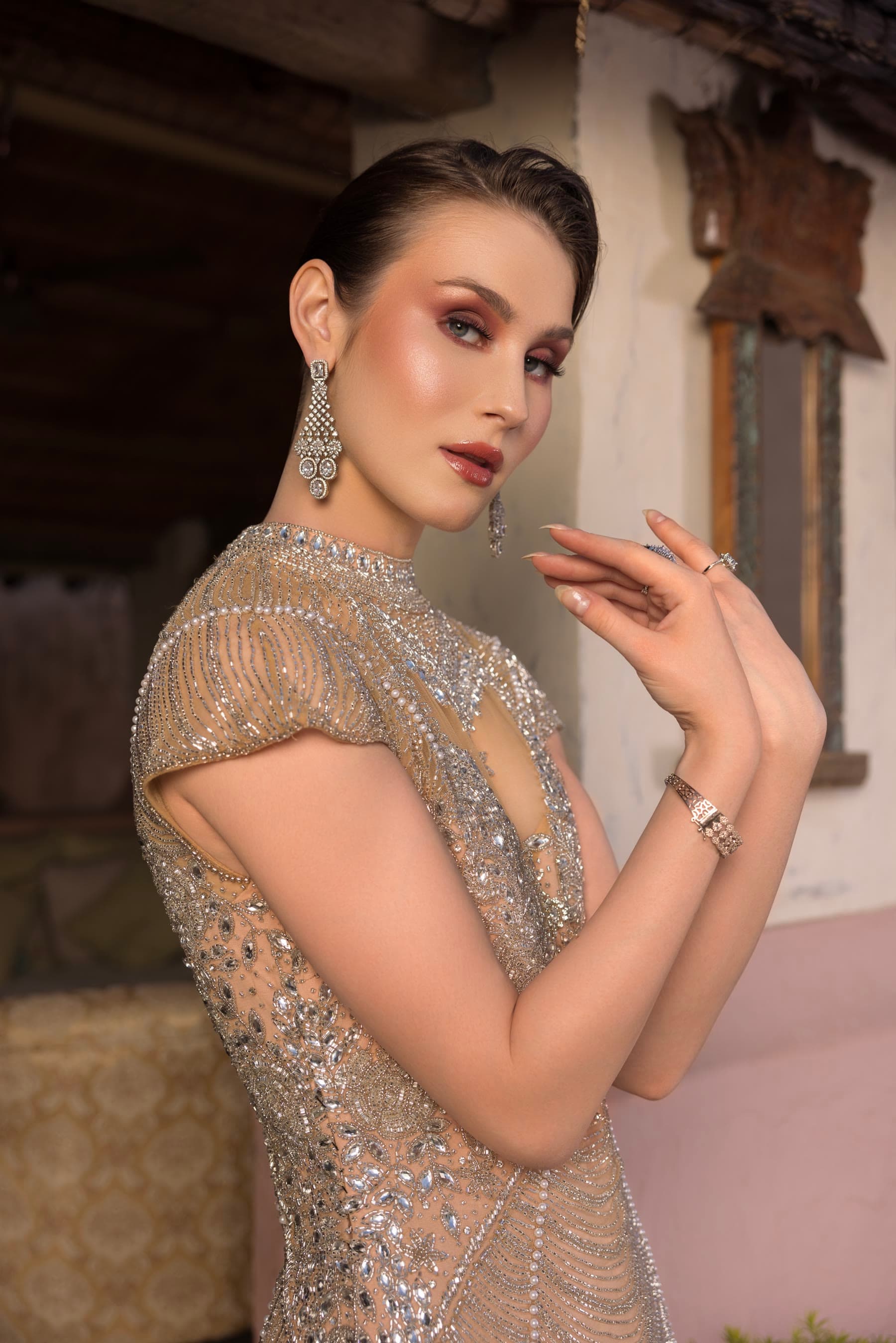 Hands lifted beside a bronzed eye, silver beading below