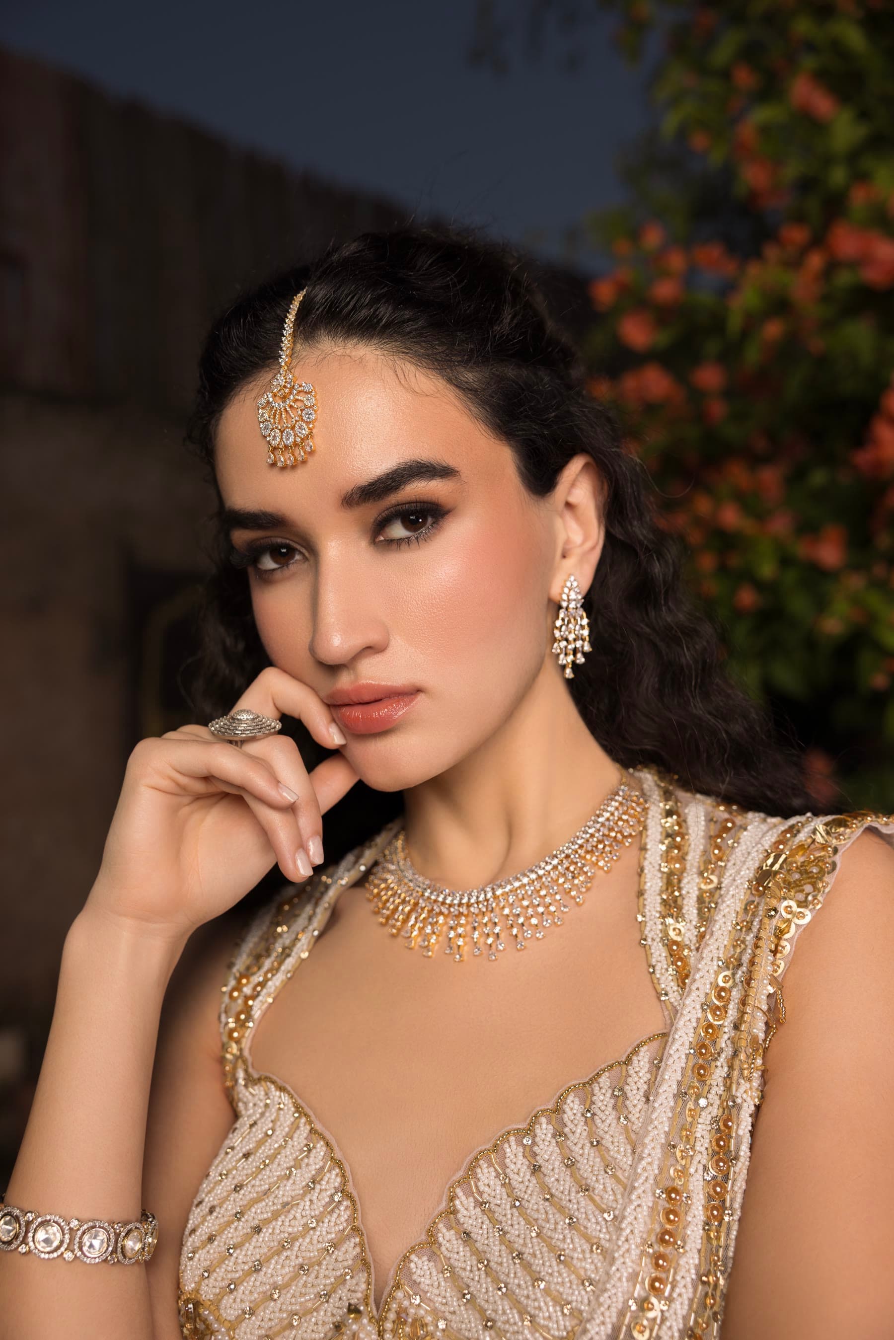 Close portrait in gold, maang tikka, the night garden behind